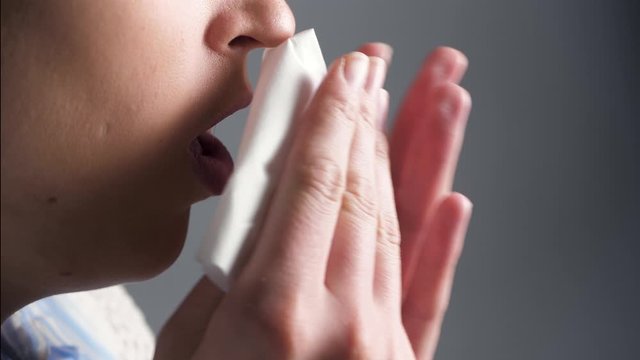 Girl coughs and covers her mouth with napkin. Colds, flu, laryngitis, tuberculosis, asthma, bronchitis, allergies, pneumonia, APF inhibitors, nasopharyngeal leakage concepts. Side view. Close-up