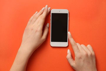 Female hands with mobile phone on color background