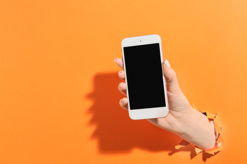 Female hand with mobile phone on color background