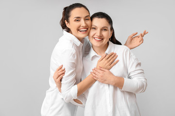 Portrait of adult daughter and her mother on grey background