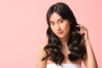 Young Asian woman with beautiful long hair on color background