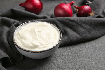 Bowl of tasty sour cream and onion on table