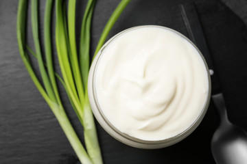 Jar of tasty sour cream and green onion on dark table