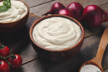 Bowl of tasty sour cream and vegetables on table