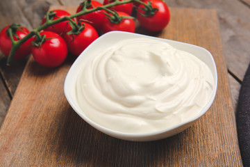 Bowl of tasty sour cream and tomatoes on wooden table