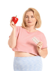 Woman with weight loss pills and pepper on white background