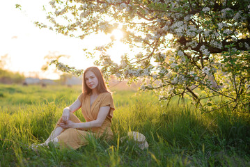 girl on sunset background near a blossoming apple tree