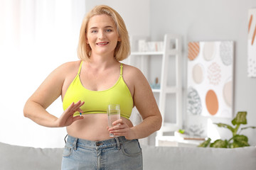 Woman with weight loss pill and water at home