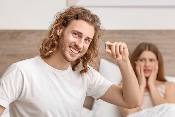 Young man with oral erectile dysfunction medication and his wife in bedroom