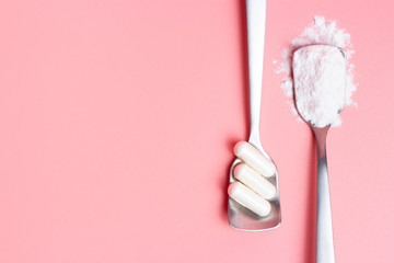 Capsules and collagen powder in spoons on pink background, copy space.