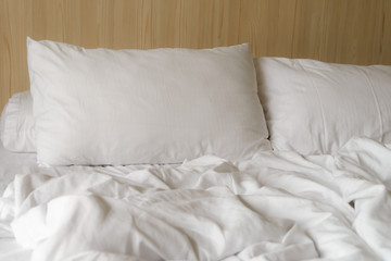 wrinkled white blanket with soft pillows on comfortable bed in the morning. messed up after nights sleep