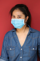 Masked Asian woman prevent germs on red background. Tiny Particle or virus corona or Covid 19 protection.