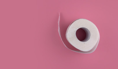 A roll of white toilet paper on a pink background copy space. Shortage of toilet paper flat lay.