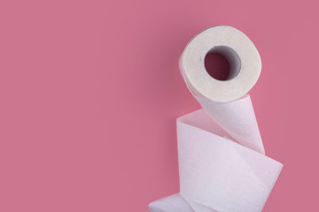 A roll of white toilet paper on a pink background copy space. Shortage of toilet paper flat lay.