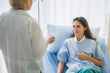 Obraz premium Senior woman doctor and patient discussing and making notes about symptom problem while she lay down on the bed.