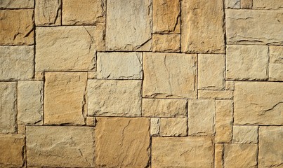 Rustic exterior wall made from brown flat natural stones of different sizes arranged randomly....