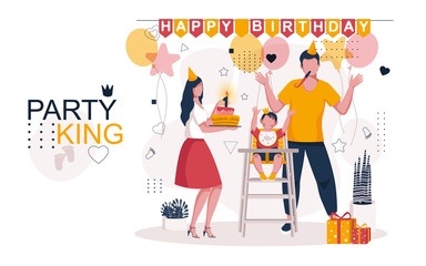 The family celebrates the birthday of the child. Mom has a birthday cake with a burning candle in her hands, daddy with a pipe in his mouth, a happy baby has raised his hands up. Family celebration.