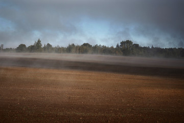 smoke in the field and cloudy sky