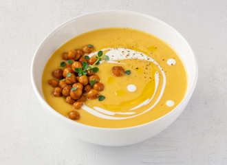 Pumpkin cream soup decorated with spicy chickpeas, sour cream, olive oil, pepper. Close up. Isolated. Vegetarian, healthy food, diet, recipe or menu concept. Grey background. 