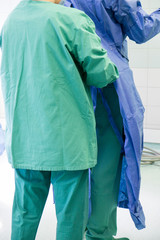 OP Saal in einem Krankenhaus, ein Pfleger zieht dem Arzt einen sterilen Kittel an