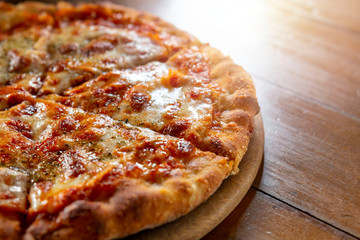 Ham and Cheese Pizza. Hot pizza slice with dripping mozzarella cheese. Pizza with cheese on board and wooden table background. Pizza slice with melting cheese. Selective focus.