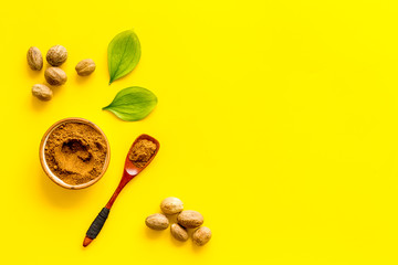 Nutmeg - spices in powder and whole nuts - on yellow background top-down copy space