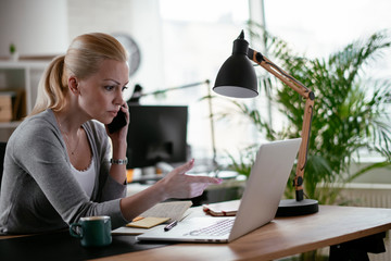 Businesswoman using phone. Happy young woman talking on smartphone in office.	