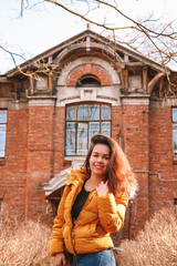 Portrait of a girl with long hair in a yellow jacket against the background of a historic old building