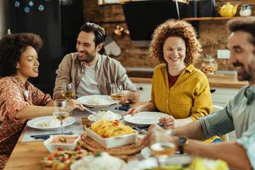 Young happy woman having lunch with her friends at home.