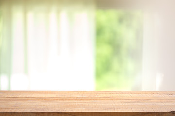 Empty wood table with blur curtain with window green garden from background.