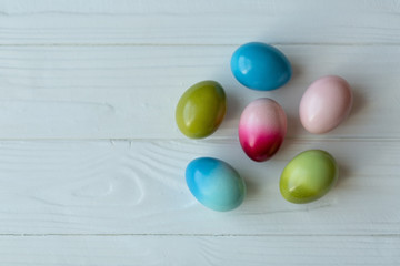 Six Easter eggs in pink, green and blue colors on white wooden background. Copy space, Easter wallpaper. Happy Easter!