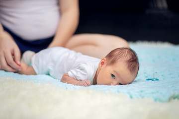 Young mother puts her newborn baby on her tummy on the couch