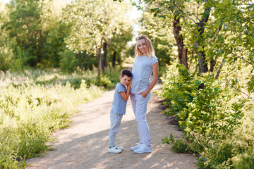 a boy hugs a pregnant mother 's stomach. photo session of pregnant women in the summer