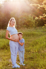 Fototapeta premium a child hugs the belly of a pregnant woman in the summer in a Park