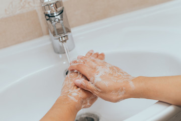 Woman use soap and washing hands under the water tap. Hygiene concept hand detail.
