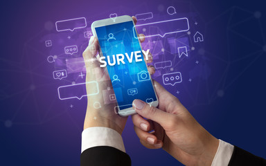 Female hand typing on smartphone with SURVEY inscription, social media concept
