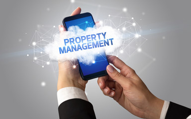 Female hand touching smartphone with PROPERTY MANAGEMENT inscription, cloud business concept