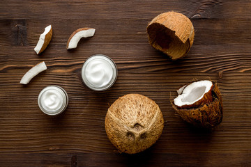 Skin care cream with coconut oil on dark wooden background top-down