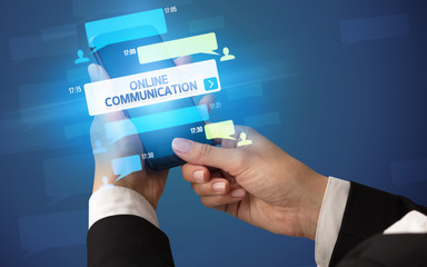 Female hand typing on smartphone with ONLINE COMMUNICATION inscription, social networking concept