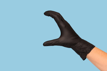 hand in a black medical glove holds an object on a blue background. Mock up, you can insert your...