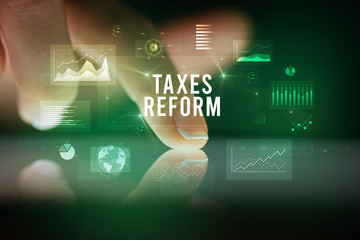 Finger touching tablet with charts and TAXES REFORM inscription, business concept