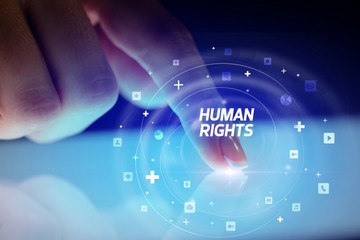 Finger touching tablet with social media icons and HUMAN RIGHTS