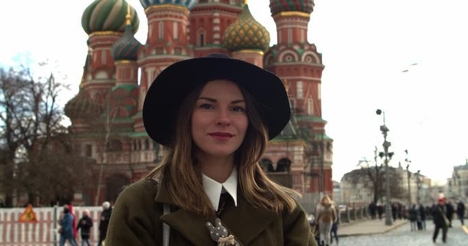 Stylish woman in black hat looking at the camera in red square, St. Basil's Cathedral on the background