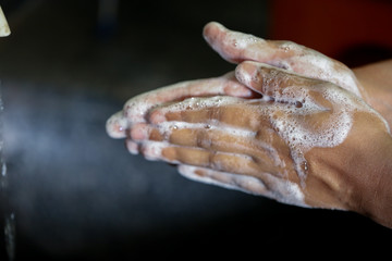 man use soap and washing hands under the water tap