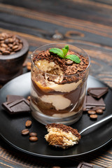 Classic tiramisu dessert in a glass cup on wooden background