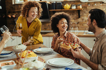Happy friends talking while eating appetizer before the lunch at dining table.