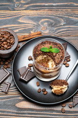 Classic tiramisu dessert in a glass cup on wooden background
