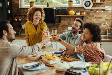 Young happy people having fun while toasting with wine during lunch.