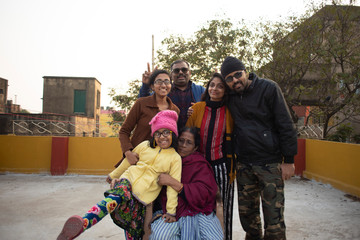 A cheerful Indian Bengali family in winter garments enjoying in a sunny winter afternoon on a rooftop. Indian lifestyle.