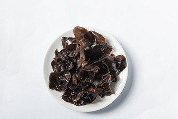 Dried agaric is isolated in a wooden bowl on a white background. Tile (top) driven fengus